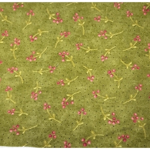 May include: Close-up of a green fabric with a repeating pattern of small pink flowers and yellow stems. The fabric has a textured appearance with tiny black dots scattered across the surface. The floral design is evenly spaced.