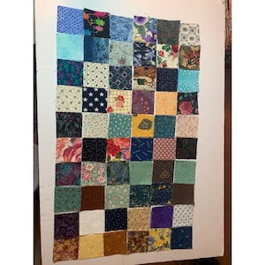 May include: A patchwork quilt block with a variety of colorful fabric squares. The squares are arranged in a grid pattern and feature floral, geometric, and abstract designs.