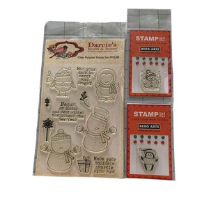 May include: Clear polymer stamp set featuring winter-themed designs. Includes stamps of snowmen, penguins, and a bird, along with festive phrases. Also includes two sets of clear stamps with gems.
