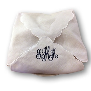 May include: White linen bread basket liner with scalloped edges and a navy blue embroidered monogram "S.H.K."