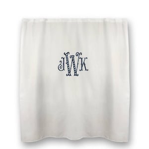 May include: White curtain with a navy blue monogram of the letters JWK. The monogram is in a decorative font with swirls and dots. The curtain is hanging and has a slight wave at the bottom.