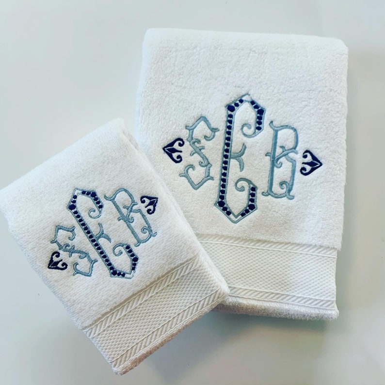 May include: Two white towels with blue and gray embroidered monograms. The monogram is a traditional script style with the letters "S.P.B."