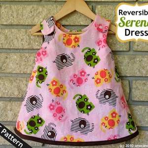 Op de afbeelding: Een roze, mouwloze jurk met een bruine zoom en een patroon van kleurrijke olifanten en bloemen. De jurk is omkeerbaar en heeft een label met de tekst "Reversible Serena Dress". De tekst "PDF Pattern" is zichtbaar in de linkerbenedenhoek van de afbeelding.