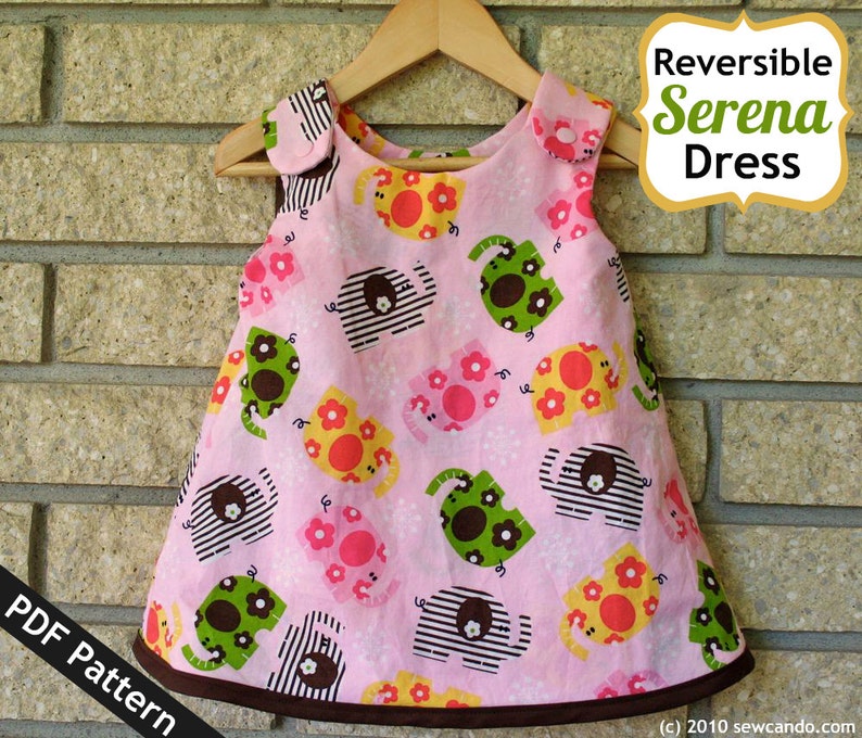 Op de afbeelding: Een roze, mouwloze jurk met een bruine zoom en een patroon van kleurrijke olifanten en bloemen. De jurk is omkeerbaar en heeft een label met de tekst "Reversible Serena Dress". De tekst "PDF Pattern" is zichtbaar in de linkerbenedenhoek van de afbeelding.