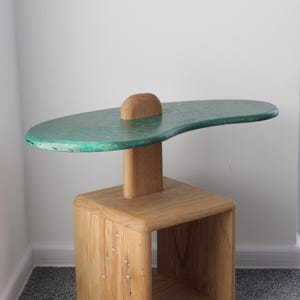 May include: A unique side table with a green, organic-shaped top and a wooden base with a shelf. The table is made of wood and has a rustic, handmade look.