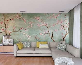 Puede incluir: Un sofá seccional gris claro con un fondo de papel tapiz floral. El papel tapiz presenta un fondo verde claro con flores rosas y ramas. El sofá tiene una variedad de almohadas en amarillo, gris y blanco.