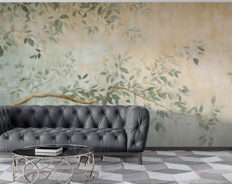 Puede incluir: Un mural de estilo acuarela que presenta una gran rama de árbol con hojas verdes sobre un fondo amarillo claro y azul. El mural se muestra en una pared detrás de un sofá gris capitoné.