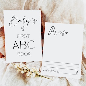 Può includere: Due carte bianche con testo nero. La prima carta dice "Baby's First ABC Book". La seconda carta dice "A is for" e ha uno spazio vuoto per scrivere.