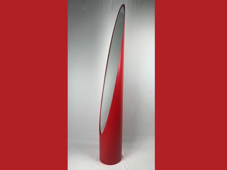 May include: A tall, red, modern floor mirror with a sleek, curved design. The mirror has a silver reflective surface and a bold, minimalist aesthetic, suitable for home decor.