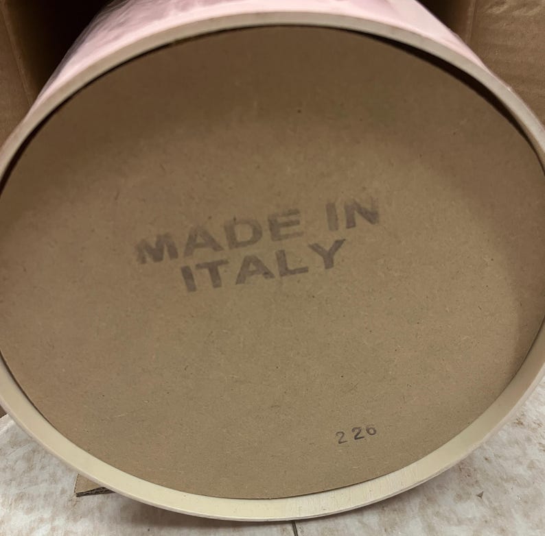 May include: A round, light brown cardboard base with the text "MADE IN ITALY" stamped in gray. The number "226" is printed in the bottom right corner. The base is part of a cylindrical container.