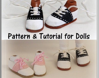 May include: A tutorial for making saddle shoes for dolls. The image shows two pairs of doll-sized saddle shoes, one pair in black and white and the other in pink and white. The shoes are made of fabric and have laces. The text "Saddle Shoes" and "Pattern & Tutorial for Dolls" is visible in the image.