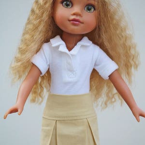 May include: A doll with long, curly blonde hair wearing a white collared shirt and a beige pleated skirt.