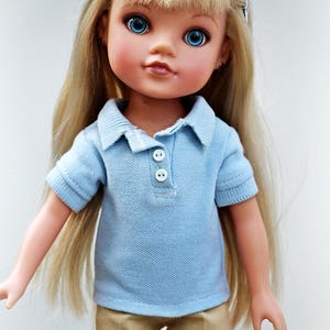 May include: A doll with long blonde hair wearing a light blue polo shirt and khaki shorts.
