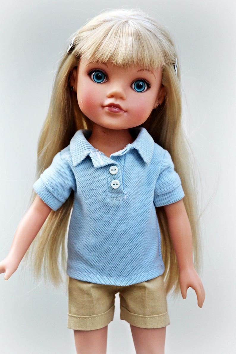May include: A doll with long blonde hair wearing a light blue polo shirt and khaki shorts.