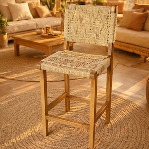 May include: A wooden bar stool featuring a square seat and a rectangular backrest, both woven with natural tan fiber in a geometric pattern. The frame is constructed from smooth, medium-toned wood with four straight legs and integrated footrests.