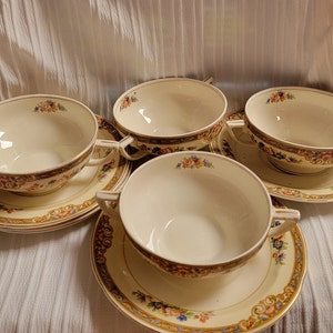 May include: Set of four vintage floral patterned soup bowls with matching saucers. The bowls and saucers are white with a gold trim and a floral pattern in shades of pink, blue, and yellow.