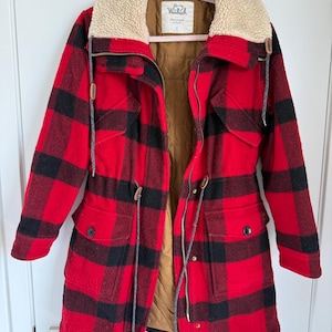 Peut inclure: Une veste à carreaux rouge et noir avec un col en sherpa crème, une doublure intérieure matelassée marron, une fermeture éclair frontale et deux poches à rabat. L'étiquette intérieure indique Woolrich et Abercrombie & Fitch, taille S.