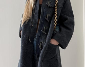 May include: A dark gray hooded duffel coat with toggle closures and a zip-up front. The coat has a long length, pockets, and a hood. A gold chain strap is visible.