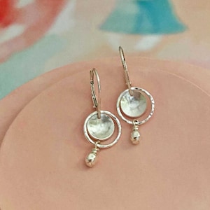 Small handmade sterling silver dangle leverback earrings. The dangle is two circles that have been hammered with a tiny beaded dangle on the bottom.