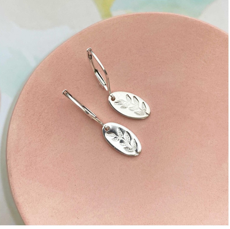 Tiny silver dangle earrings with stamped leaf design on dainty oval drop. Leverback style earwires