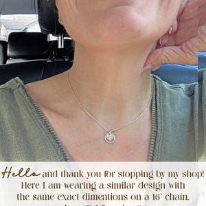May include: A silver necklace with a small, circular pendant. The pendant has a detailed design within a circular frame. The necklace is worn on a person. The image includes the text: "Hello and thank you for stopping by my shop! Here I am wearing a similar design with the same exact dimentions on a 16" chain."