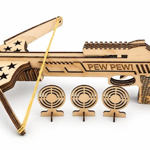 May include: A wooden toy crossbow with the text "PEW PEW!" and three target practice cutouts. The crossbow has a suction cup tip and a yellow rubber band. The design includes star cutouts.