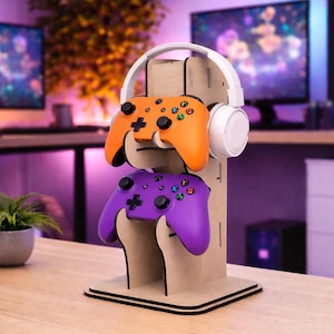 May include: A wooden gaming stand with an orange and purple game controller, and a white headset. The stand is designed to hold two controllers and a headset, keeping gaming accessories organised and accessible.