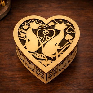 May include: A heart-shaped wooden box with a laser-cut design featuring two cats facing each other. The box is gold-colored and sits on a dark wooden surface. The design includes hearts and other decorative elements.