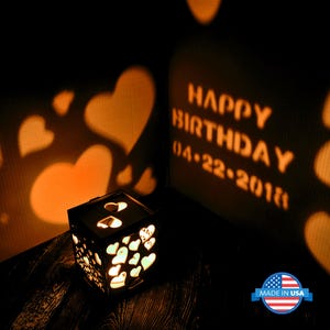 May include: A wooden box with a light inside that projects a shadow of hearts and the text "Happy Birthday 04-22-2018" onto a wall. The box is decorated with small hearts.