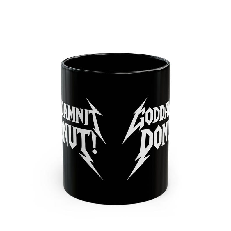 Black ceramic mug with bold white text in a Metallica-style font that reads “Goddamnit Donut,” inspired by Dungeon Crawler Carl. The mug is set on a modern kitchen counter, perfect for fans of LitRPG, Princess Donut, and Matt Dinniman's cult book series. Ideal for coffee or tea lovers who enjoy a mix of humor, chaos, and fandom in their daily routine.