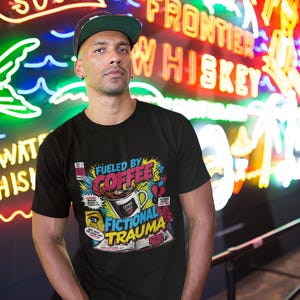Man wearing black Fueled by Coffee and Fictional Trauma bookish tee in front of colorful neon bar signs, vibrant nightlife lifestyle photo