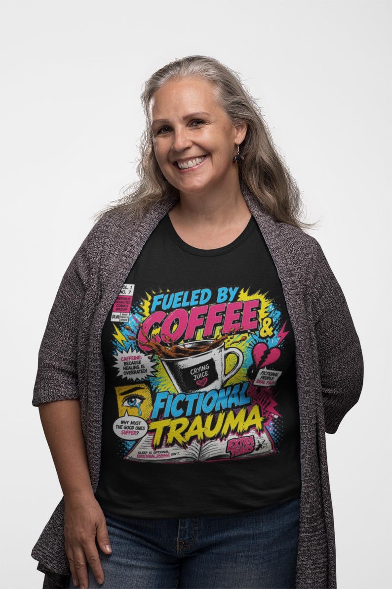 Woman wearing black Fueled by Coffee and Fictional Trauma bookish tee with grey cardigan, colorful comic print, funny reader gift shirt for book lovers