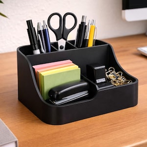 May include: A black desk organizer with multiple compartments containing various office supplies including pens, scissors, a stapler, a stack of colorful sticky notes, and gold-toned binder clips. The organizer has a tiered design for storage.