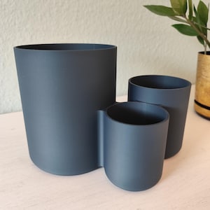 May include: A white ceramic mug with a black handle and the text "But First, Coffee" in a black, bold font. The mug is on a white surface.