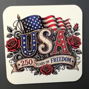 May include: A square coaster featuring a graphic of the American flag waving behind the text USA in red, white, and blue. Below, a banner reads 250 YEARS OF FREEDOM, surrounded by red roses and black scrollwork on a white background.