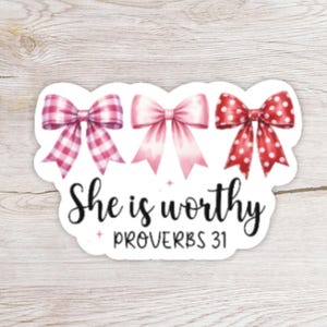 May include: A sticker featuring three decorative bows in pink hues. The bows have different patterns, including gingham and polka dots. The text "She is worthy" and "Proverbs 31" are written in black script below the bows.