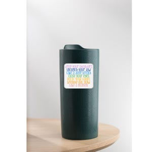 May include: A green travel mug with a white sticker that says "drop your shoulders, unclench your jaw, take a deep breath, close your eyes, relax your hands, breathe out slow, take a moment."