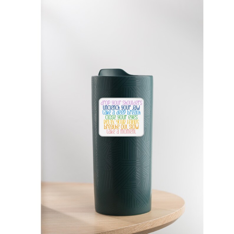 May include: A green travel mug with a white sticker that says "drop your shoulders, unclench your jaw, take a deep breath, close your eyes, relax your hands, breathe out slow, take a moment."