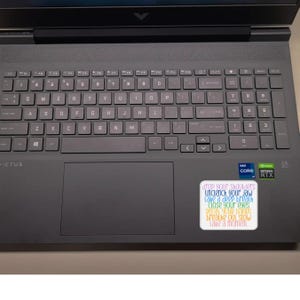 May include: A gray laptop computer with a sticker that reads "drop your shoulders, unclench your jaw, take a deep breath, close your eyes, relax your hands, breathe out slow, take a moment".