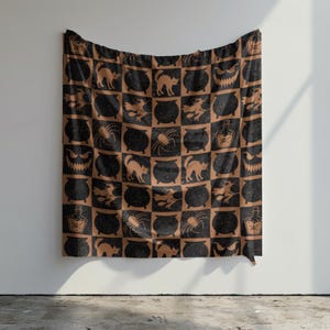 May include: A rectangular fabric wall hanging featuring a repeating checkerboard pattern in black and orange. The design includes illustrations of black cats, cauldrons, spiders, witches on broomsticks, potion bottles, and grinning jack-o'-lantern faces.