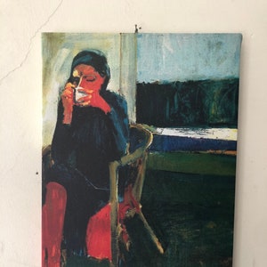 Puede incluir: Una pintura de una persona sentada en una silla y bebiendo de una taza. La persona lleva una camisa negra y pantalones rojos. El fondo es verde oscuro y azul.