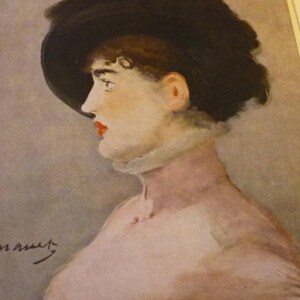 May include: Watercolor portrait of a woman in profile, wearing a large black hat and a high-collared, light-colored garment. Her lips are painted red, and her skin has a pale, rosy hue. The background is a soft, muted gray.