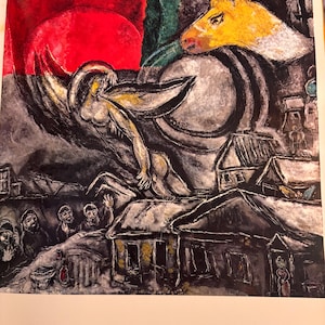 Pode incluir: Uma pintura de Marc Chagall intitulada "Pâques" que retrata uma cena de uma aldeia com casas, um sol vermelho, um touro amarelo e uma figura com asas voando sobre a aldeia. A pintura é feita em um estilo que é característico do trabalho de Chagall, com cores fortes e linhas expressivas.