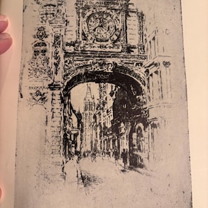 Puede incluir: Un grabado en blanco y negro del Gros Horloge en Rouen, Francia. La imagen representa una gran torre del reloj con una puerta arqueada que conduce a una calle bordeada de edificios. El texto "GROS HORLOGE ROUEN" está en la parte inferior.
