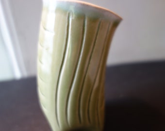 底にサイン入りの陶器の花瓶。新品同様。側面に装飾的な縞模様がある