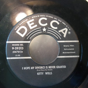 May include: Black and white vinyl record with the label "Decca" and the song title "I Hope My Divorce Is Never Granted" by Kitty Wells. The record number is 9-29313.