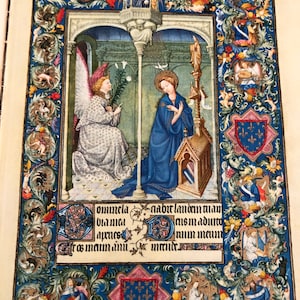 Peut inclure: Une page de manuscrit enluminé médiéval représentant l'Annonciation. La Vierge Marie est agenouillée en prière, tandis qu'un ange lui présente un lys. La page est encadrée d'une bordure décorative avec des motifs floraux et de petites figures. Le texte sur la page dit "Omnela nabit landen plan bisma adnu num maun", qui est du latin pour "Toute la terre sera heureuse, le Seigneur est venu à nous."