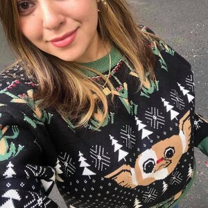 May include: Black and green Christmas sweater with a white snowflake pattern and a brown and white cartoon dog face. The sweater has a green collar.