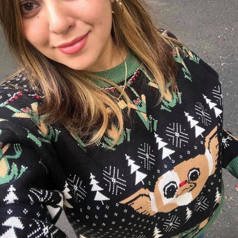 May include: Black and green Christmas sweater with a white snowflake pattern and a brown and white cartoon dog face. The sweater has a green collar.