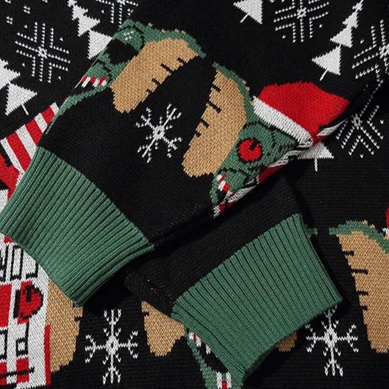 May include: A black and green Christmas sweater with a white snowflake pattern and a green creature wearing a Santa hat. The sweater has a green and black ribbed cuff.